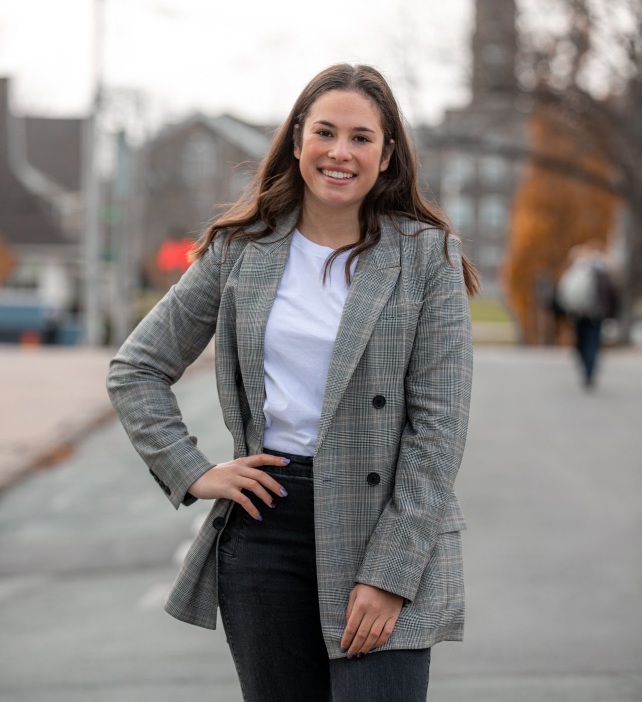 Molly Kohn is an upcoming grad of Dal's Bachelor of Management program (fall 2024) and an entrepreneur. Kohn is standing in the street dressed business casual and smiling with her hand on her hip.